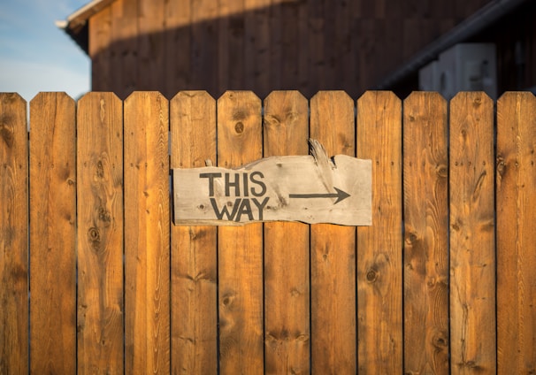 brown wooden plank fence with this way signboard