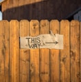 brown wooden plank fence with this way signboard