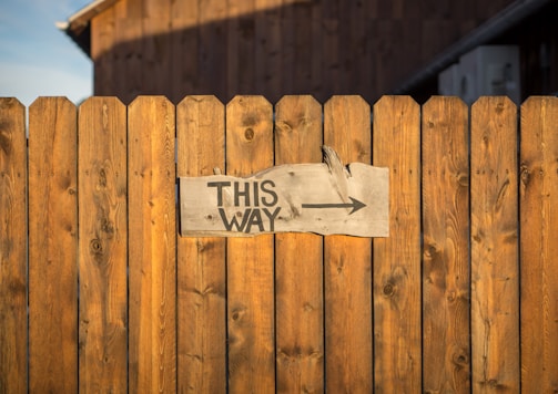 brown wooden plank fence with this way signboard