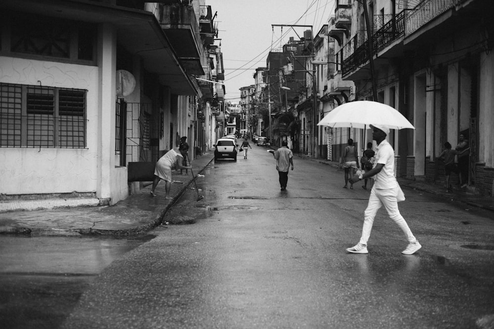Homem segurando guarda-chuva andando na estrada cinza