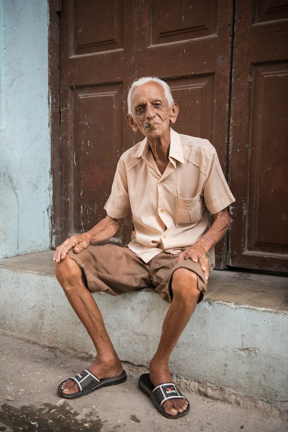 man in beige button-up shirt sitting in front of brown door