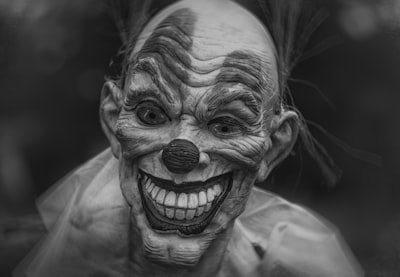 grayscale photography of person wearing clown mask scary zoom background