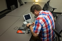 man sitting on chair and writing on desk