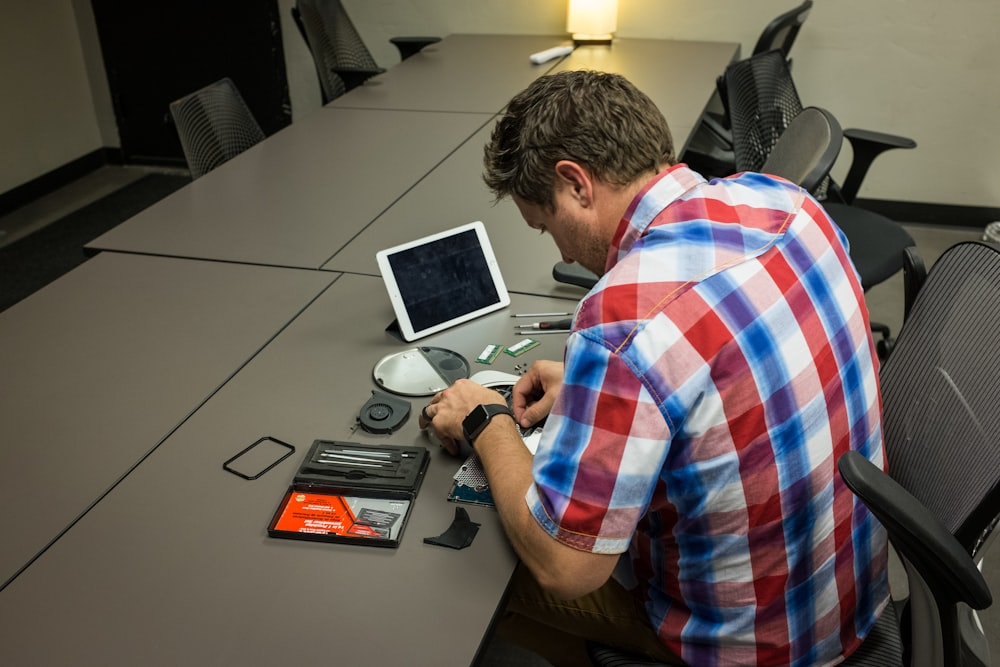 homme assis sur une chaise et écrivant sur un bureau