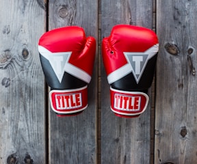 pair of red-and-black Title training gloves on grey wooden plank