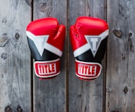 pair of red-and-black Title training gloves on grey wooden plank