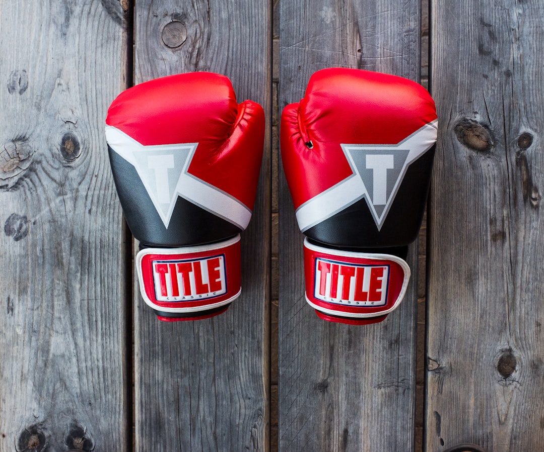  pair of red and black title training gloves on grey wooden plank match box