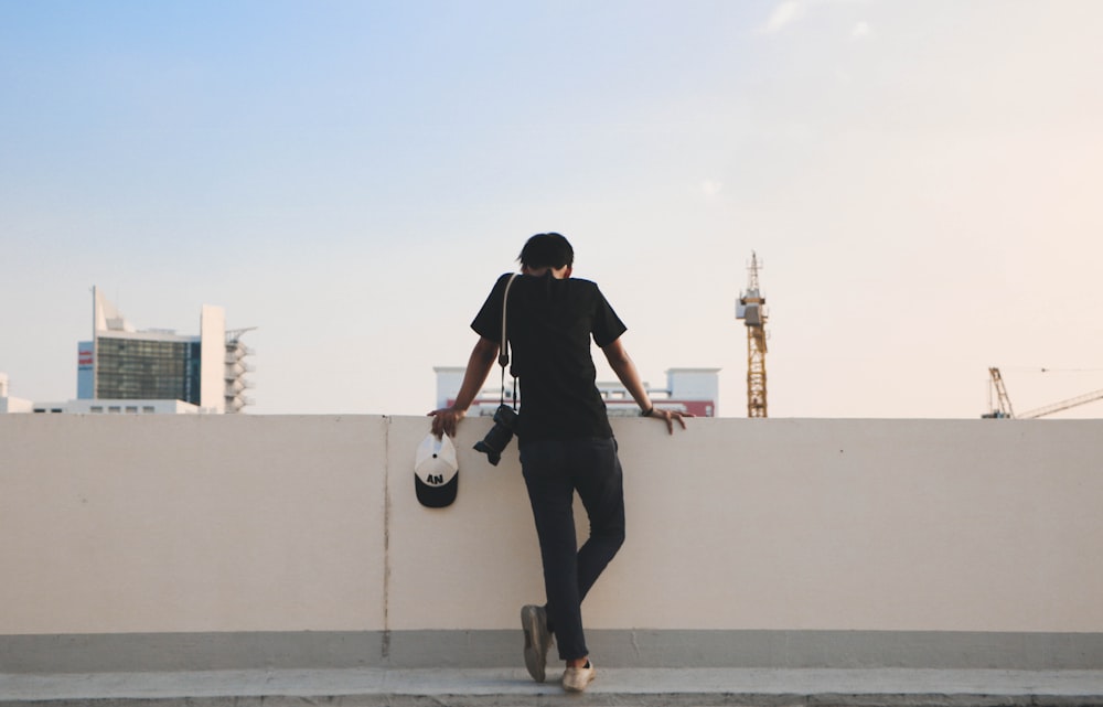 person leaning against white wall