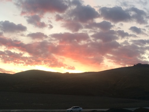 Sunset over rolling hills with the transfer van waiting on a quiet road.