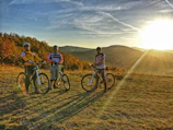 Smiling friends pausing on a hilltop with their bikes overlooking a valley