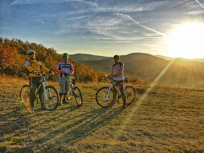 A group of riders laughing and taking a break beside their nobbytrail bikes on a mountain overlook