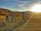 A group of women riders laughing together on their bikes at sunset, with rolling hills in the background.