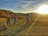 A group of women riders laughing together on their bikes at sunset, with rolling hills in the background.