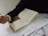 A person with a watch on their wrist is holding a pen and writing on a notebook. There are multiple sheets of paper around the notebook, filled with handwritten text. The scene suggests a study or work environment, with attention focused on writing.