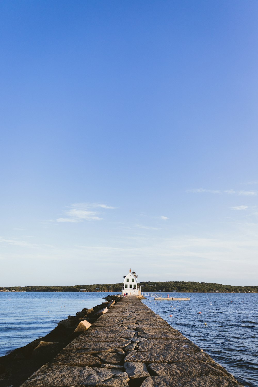 landscape photography of grey concrete docking pier with white concrete building at the end of it