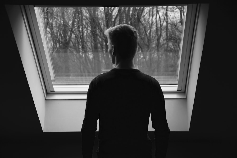 silhouette of man looking through window