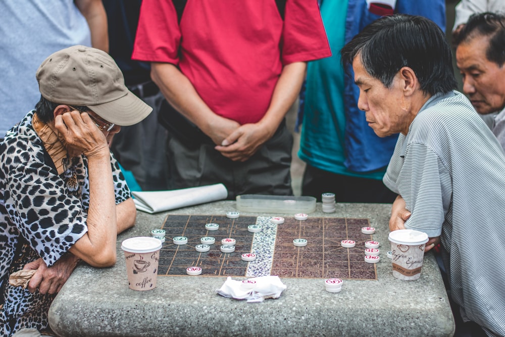 two men sitting beside table playing game