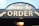 A sign for a drive-through ordering area, featuring bold wooden letters spelling 'ORDER' against a dark background, with an arrow pointing to the left. Above this, a decorative sign displays 'drive-by' with stars, and a light fixture is visible below.