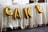 Gold foil balloons spelling out the word 'CAKE' are displayed against a lace tablecloth. The table is covered with decorative food items and containers on top.