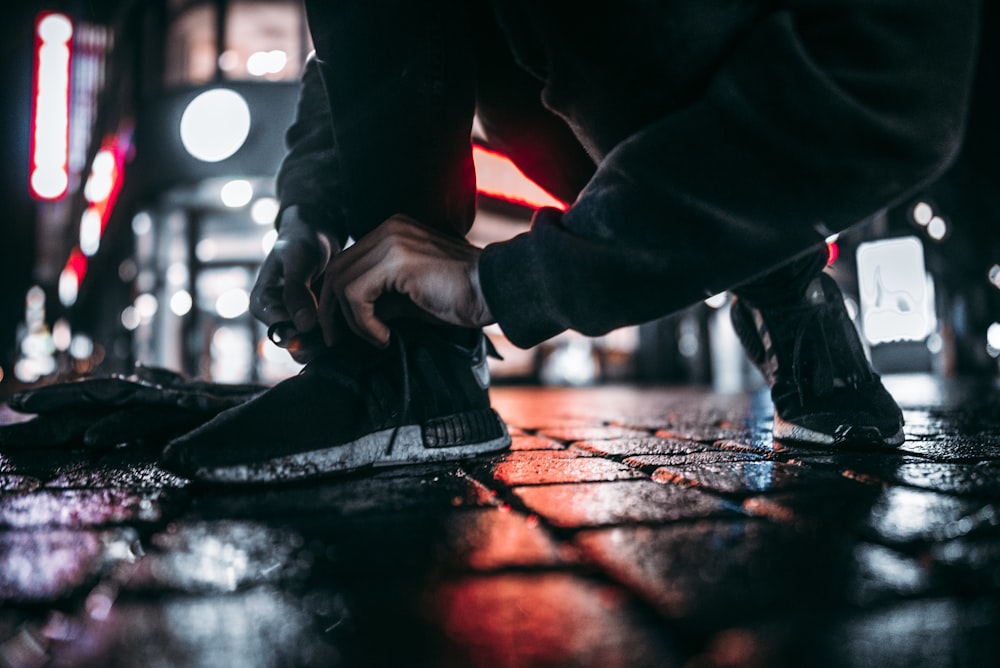 person lacing shoes on pavement