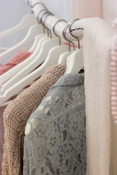 Close-up of a stylish nude-colored dress hanging on a wooden rack in a bright boutique.