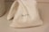A small, folded cloth bag with the word 'GRAINGER' printed in black letters. It rests on a smooth, light-colored surface with shadows indicating soft lighting.
