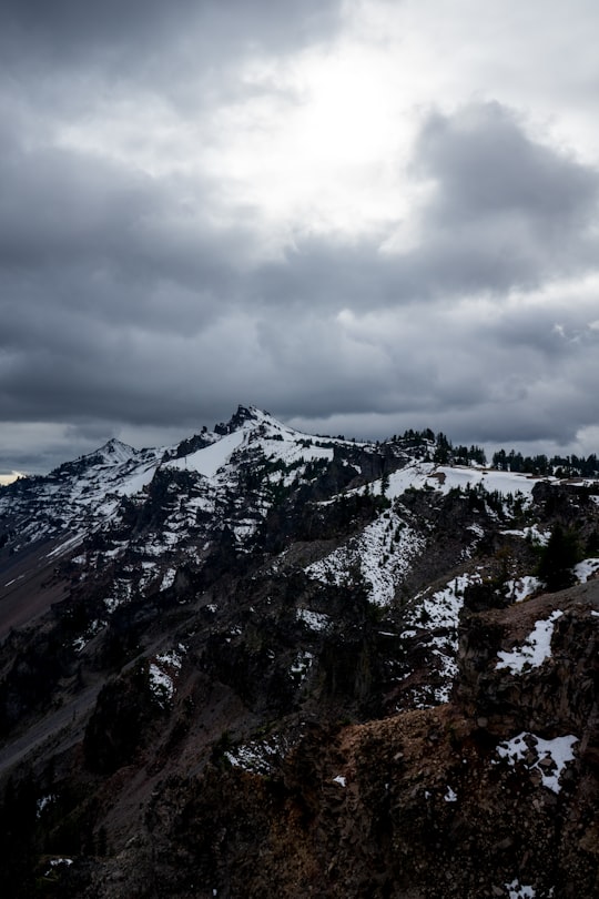 snow-covered mountain under cloudy sky in Crater Lake United States