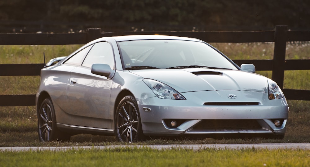 silver luxury car parked near wooden fence