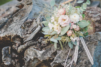 A beautifully arranged bridal bouquet with soft pastel flowers resting on a rustic wooden table.