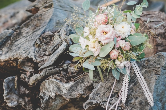An elegant wedding bouquet featuring soft pastel flowers with greenery, resting on a rustic wooden table.