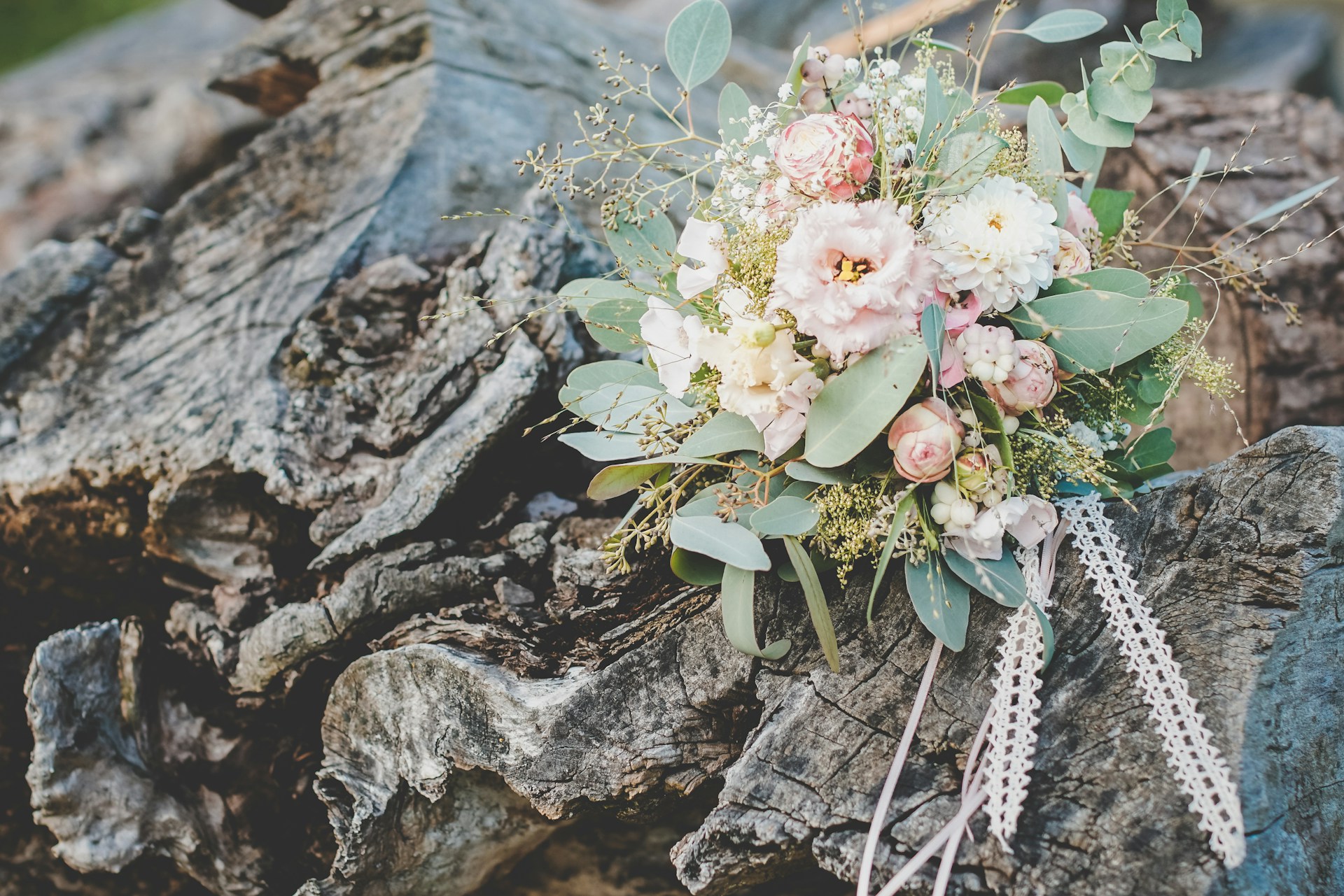 A delicate bridal bouquet featuring soft ivory roses and subtle gold accents, resting on a rustic wooden table.