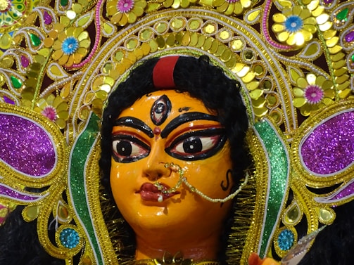 An intricate close-up of a traditional idol of Lalitha Tripura Sundari adorned with flowers.