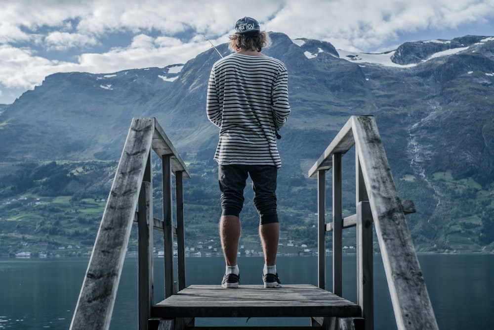 man in black and white striped sweatshirt standing on wooden dock