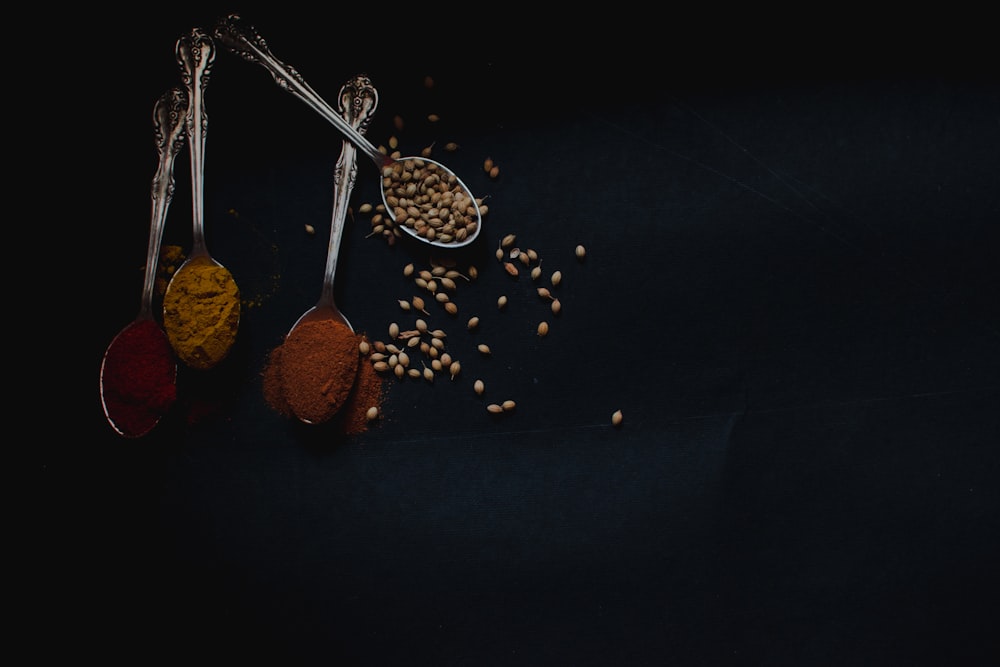 four stainless steel spoons with condiments