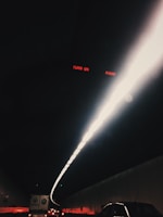 A dark tunnel illuminated by a bright, narrow line of lights along the ceiling. Several vehicles are visible in the tunnel, including cars and a truck. The red text 'TURN ON RADIO' is visible at the top.