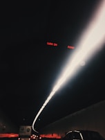 A dark tunnel illuminated by a bright, narrow line of lights along the ceiling. Several vehicles are visible in the tunnel, including cars and a truck. The red text 'TURN ON RADIO' is visible at the top.