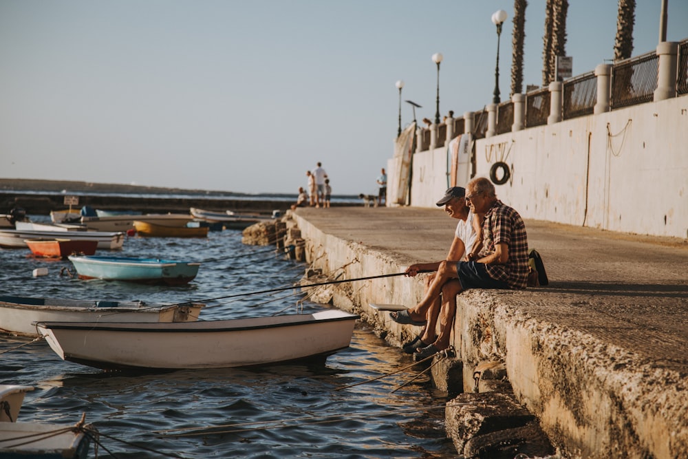 two men fishing near boats