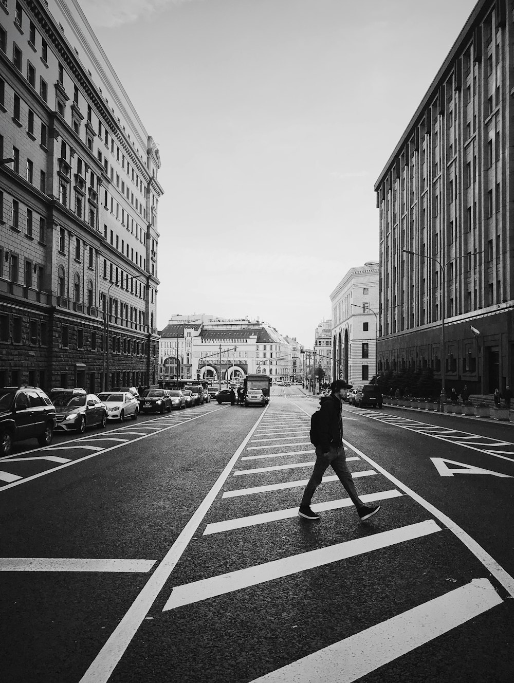 man walking on the street between high-rise building