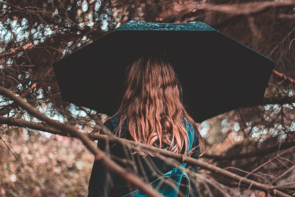 Frau steht mit schwarzem Regenschirm in der Hand