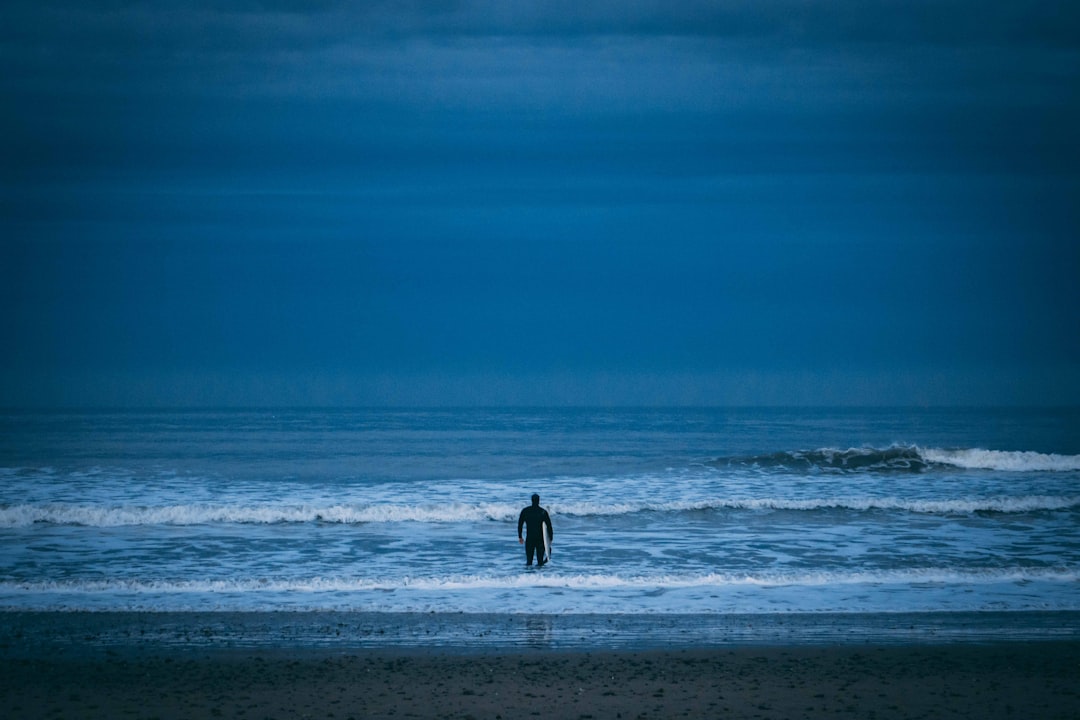 man standing on beach under cloudy sky