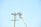A worker in a bucket lift is performing maintenance on a utility pole, wearing protective gear including a hard hat. The utility pole has multiple wires attached, and the scene is set against a clear blue sky.