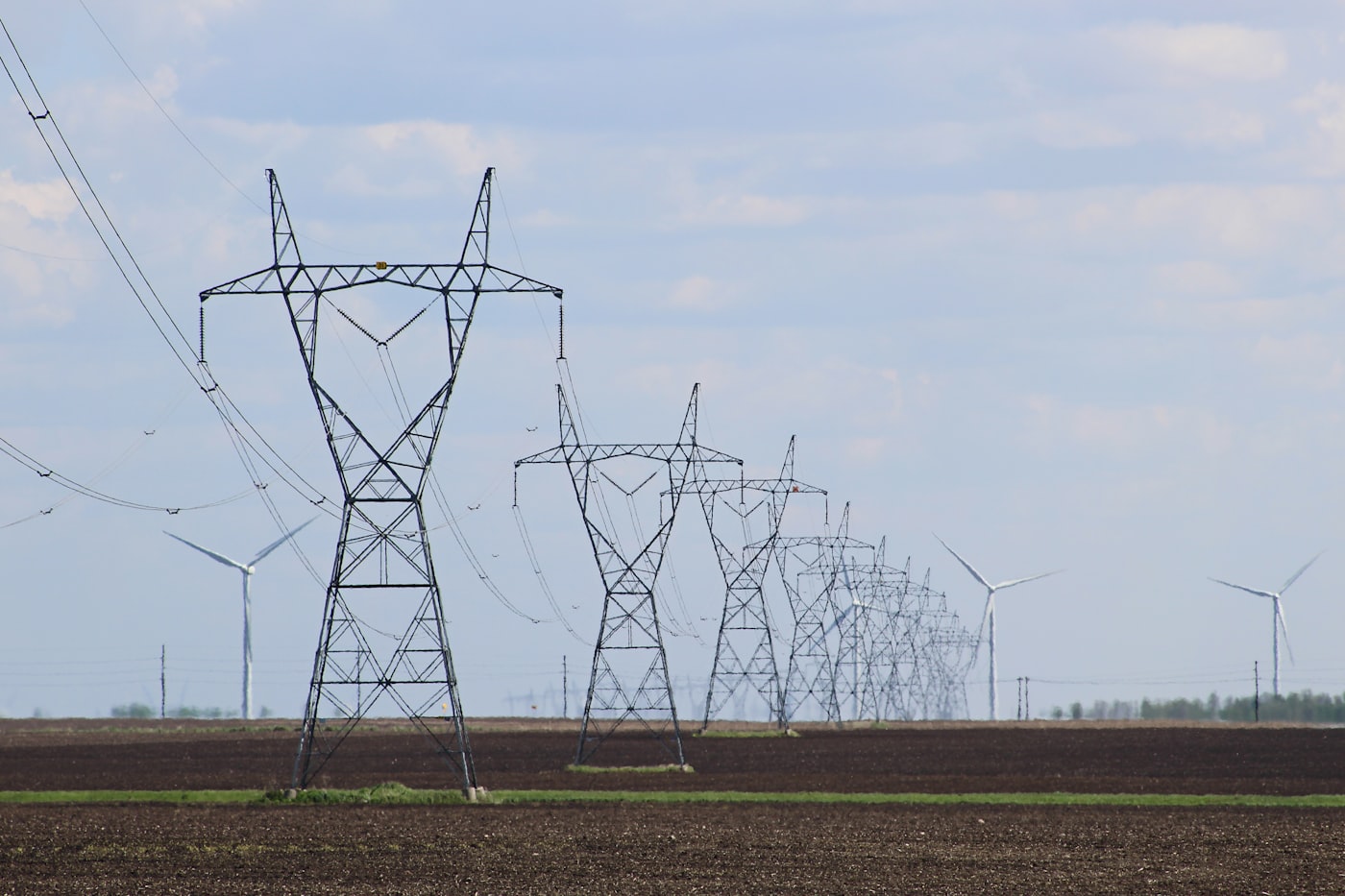 Stromleitungen und Windräder auf einem Feld