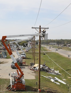 person on bucket crane truck beside utility pole during daytime