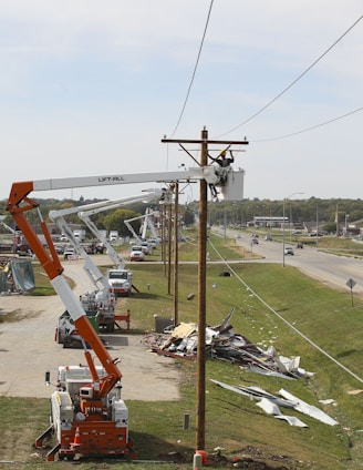 person on bucket crane truck beside utility pole during daytime