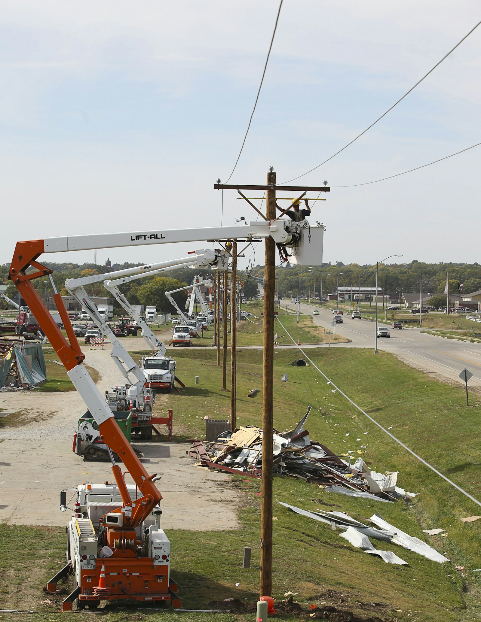 Utility lineman in a bucket truck working beside a power pole during daytime restoration.