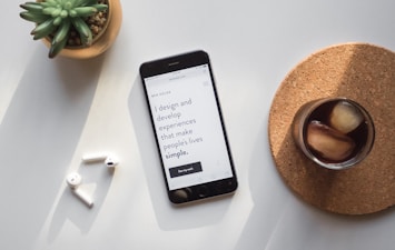 post-2014 iPhone beside Apple AirPods and succulent plant on white surface