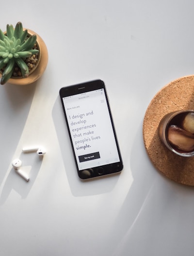 post-2014 iPhone beside Apple AirPods and succulent plant on white surface