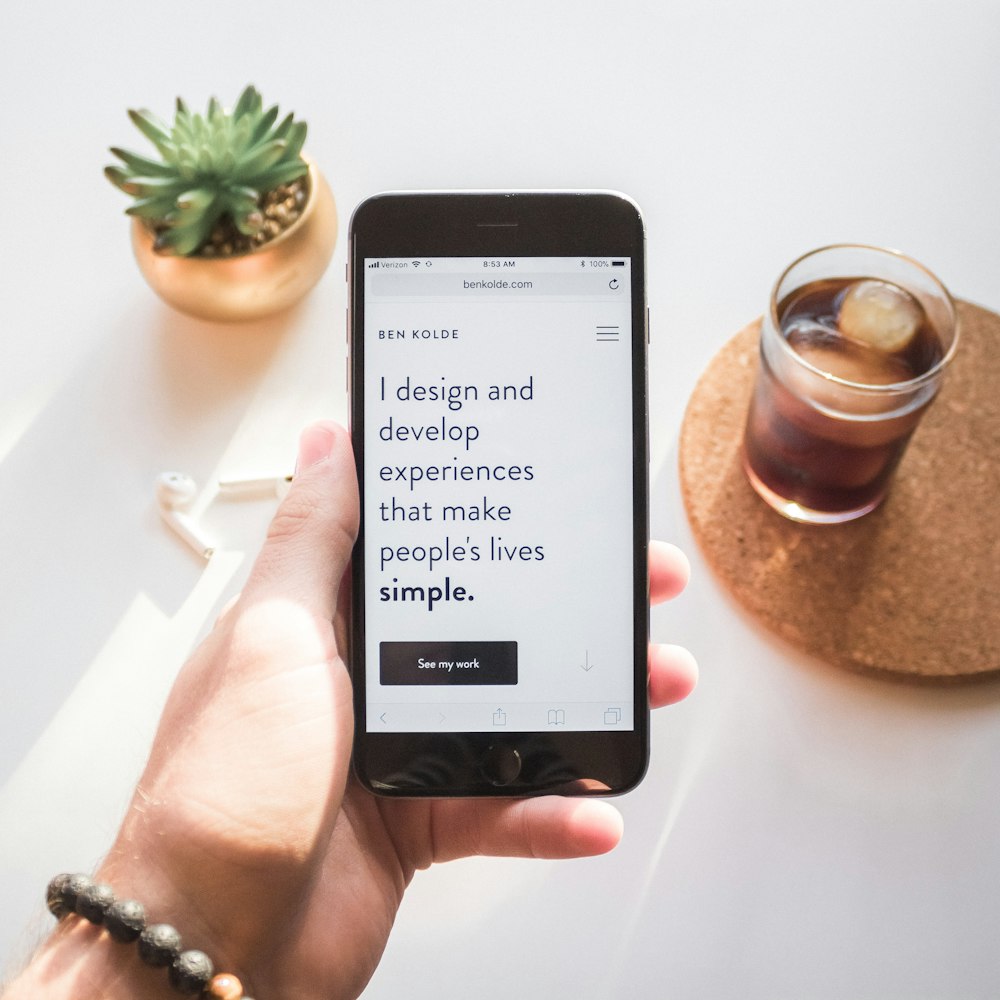 persona sosteniendo el espacio gris iPhone 6 que muestra diseño y desarrollo experiencias que hacen que la vida de las personas sea simple texto
