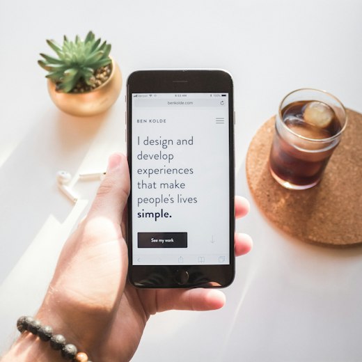 Hand holding a phone showing a portfolio site