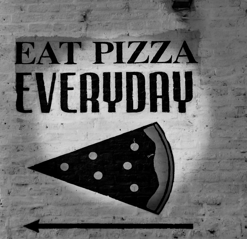 Photo en niveaux de gris de la signalisation de tous les jours de manger de la pizza